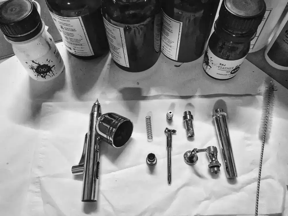 Close up of high quality modelling tools, airbrush parts, and paint bottles